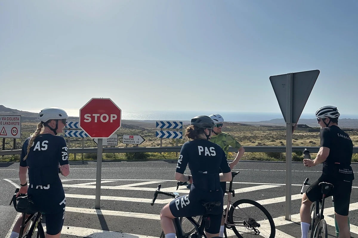 Cykelryttere holder pause ved et vejkryds på træningslejr - Coach Lykke Endurance Hviledag og restitutionsdag: cykelryttere holder pause ved stopskilt på træningslejr