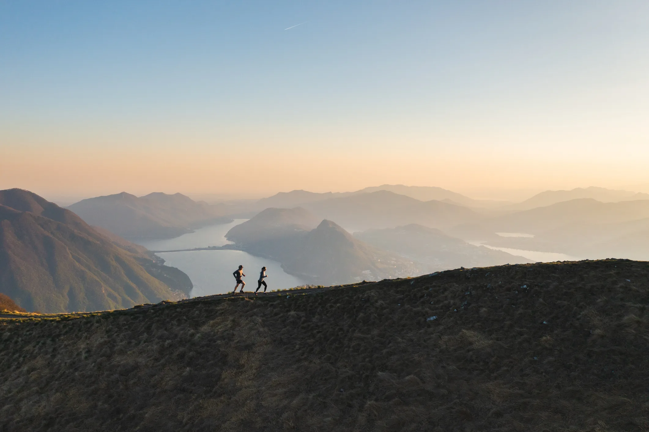 Løbeprogram: løbere på bjergryg i solnedgang - Coach Lykke Endurance To løbere på en bjergryg i solnedgang – online coaching til løb