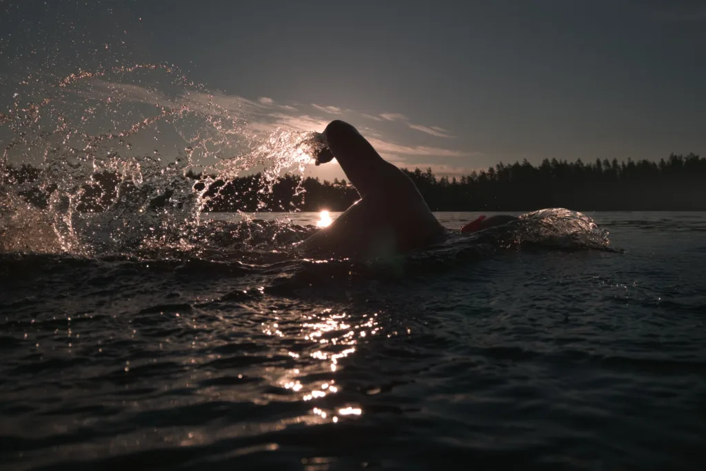 Online coaching: triatlet svømmer i solnedgang - Coach Lykke Endurance Triatlet svømmer i havet ved solnedgang – online coaching til triatlon, cykling og løb