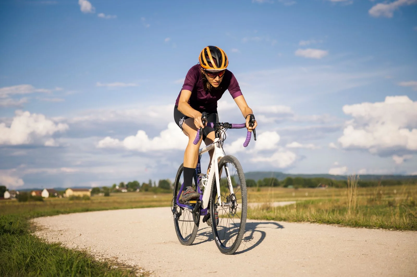 Gravel cykling – rytter på grusvej mellem marker - Coach Lykke Endurance Gravel cykling: en rytter kører på en lys grusvej mellem marker en sommerdag
