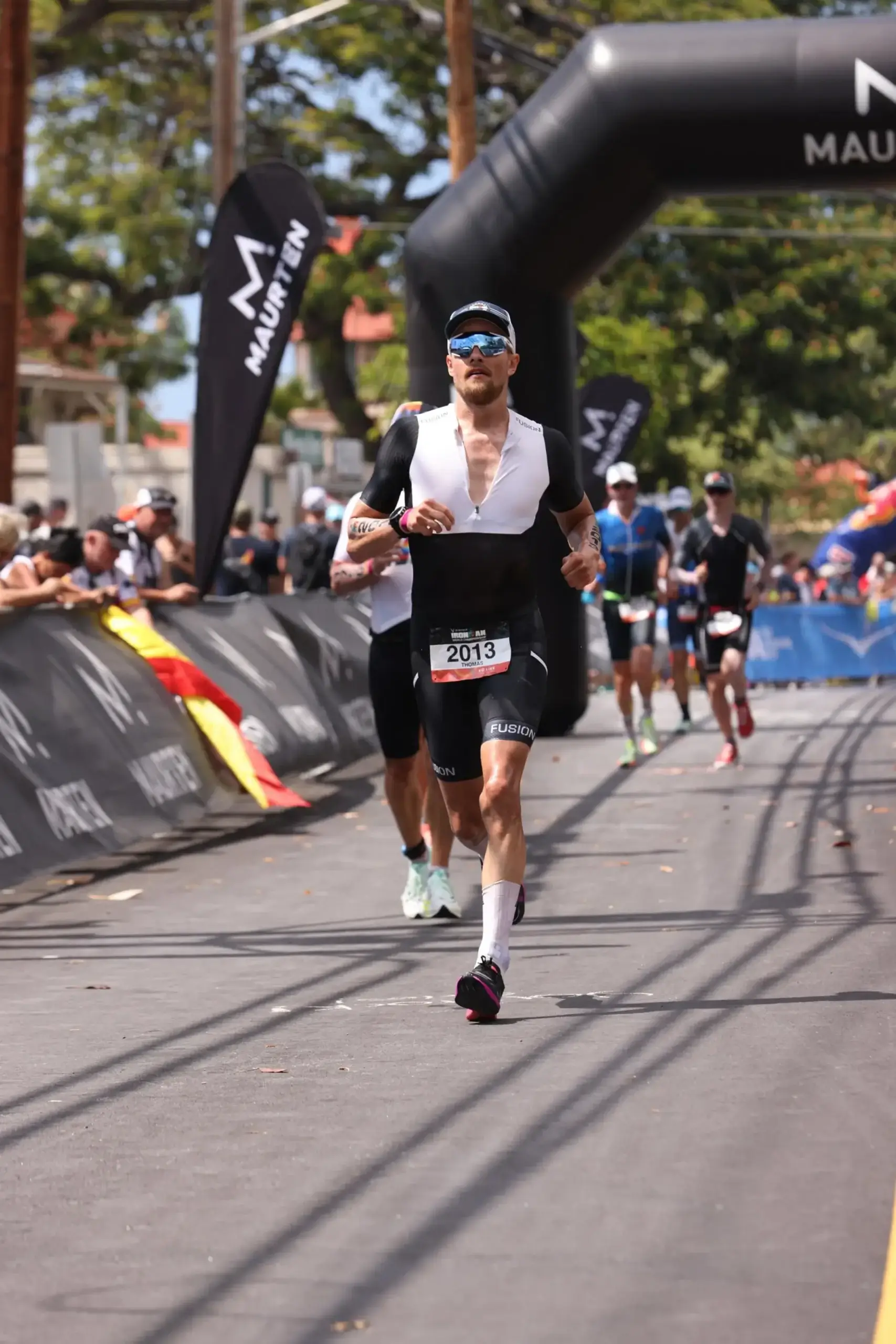 Ironman-atlet i løbesegmentet med fokus og pacing under det varme løb på Ironman-ruten.