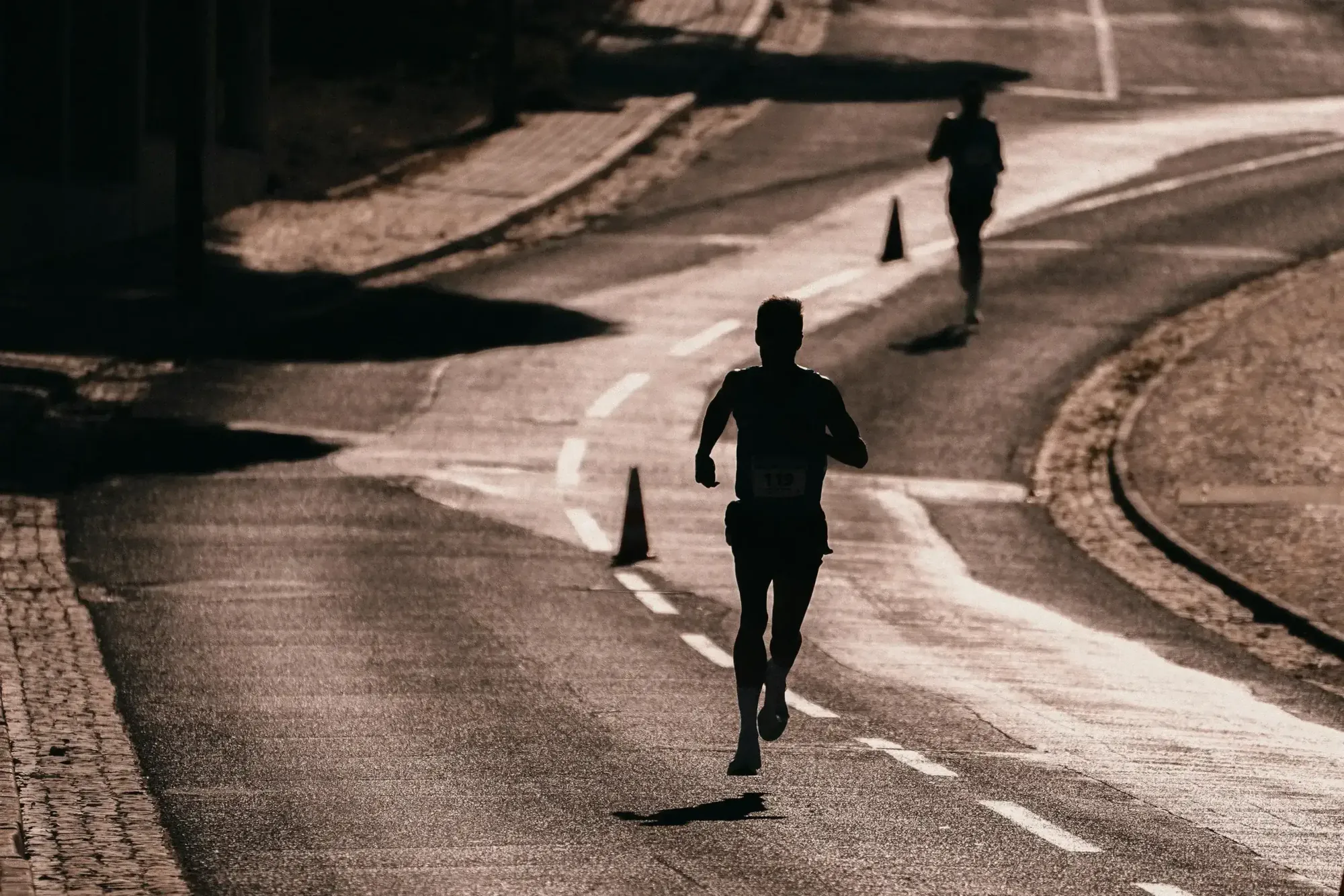Træningszoner løb: løbere på vej med kegler - Coach Lykke Endurance Løbere på en vej med kegler – træningszoner i triatlon til løbedelen