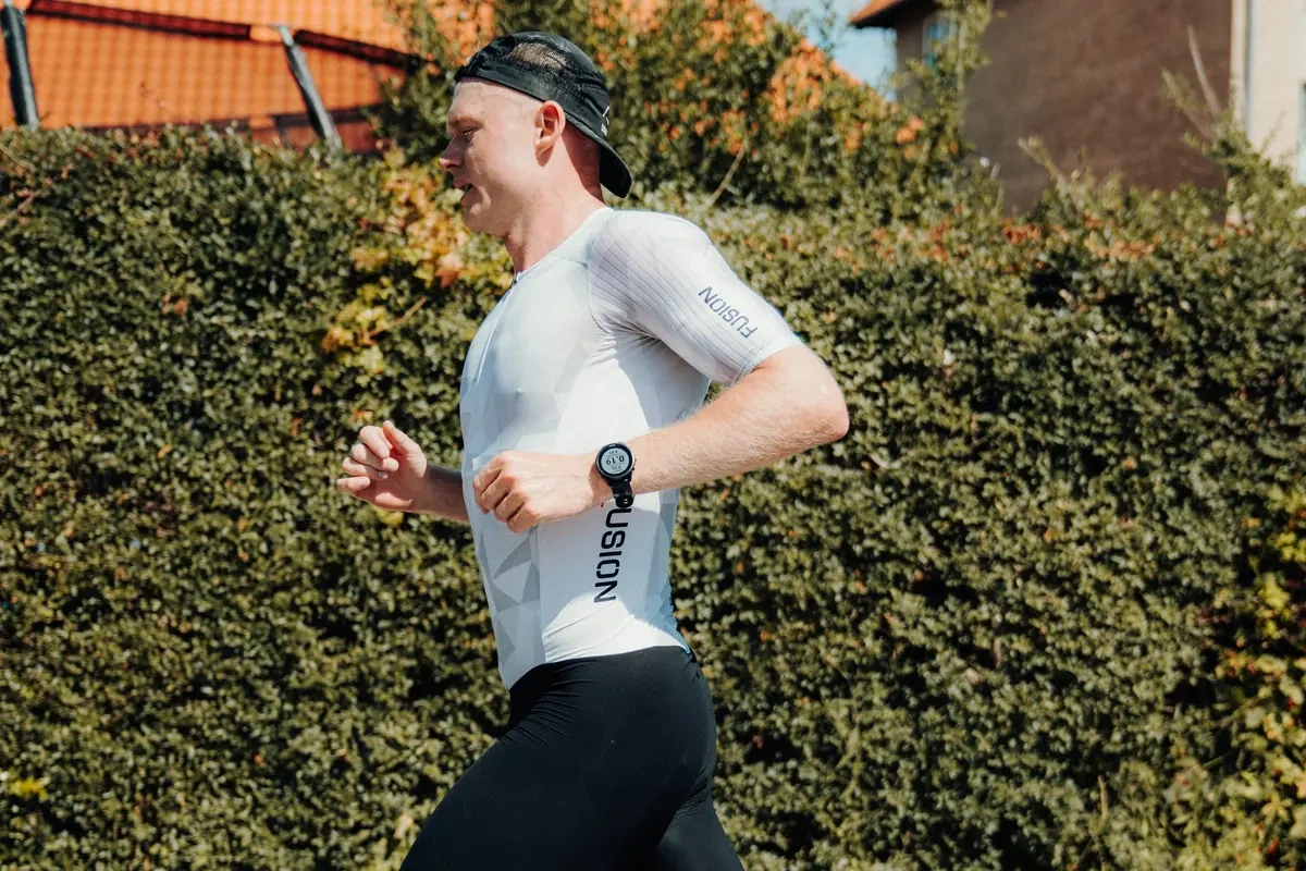 Triathlon ur - Coach Lykke Endurance Triathlon ur på håndleddet af løber i trisuit forbi en hæk