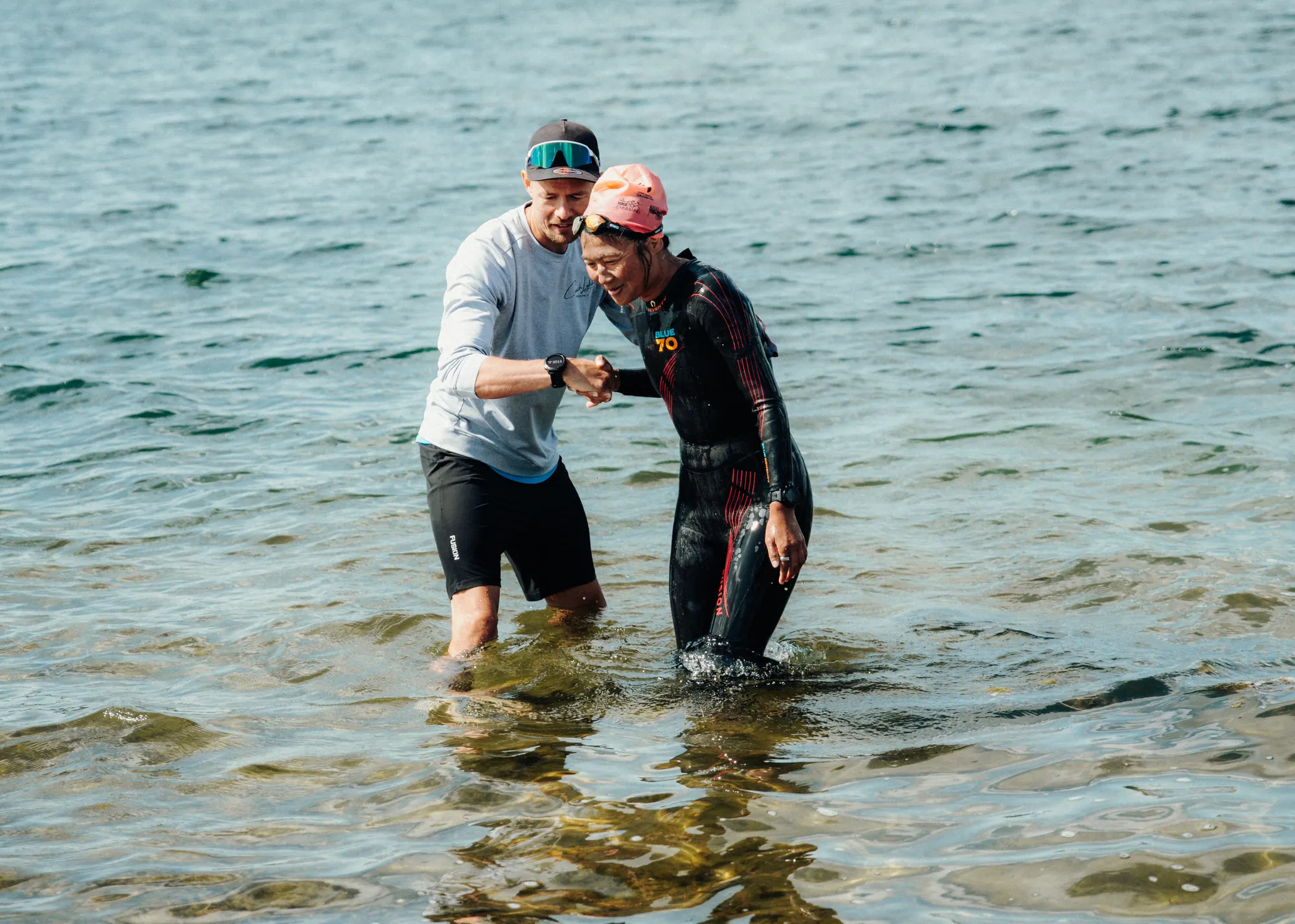 Triatlontræner instruerer en svømmer - Coach Lykke Endurance Triatlontræner instruerer en svømmer i våddragt i åbent vand